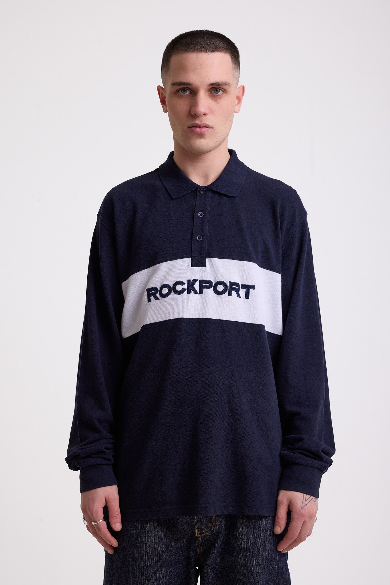 Navy long sleeve pique polo shirt with contrast chest panel and appliqué Rockport logo, worn by model
