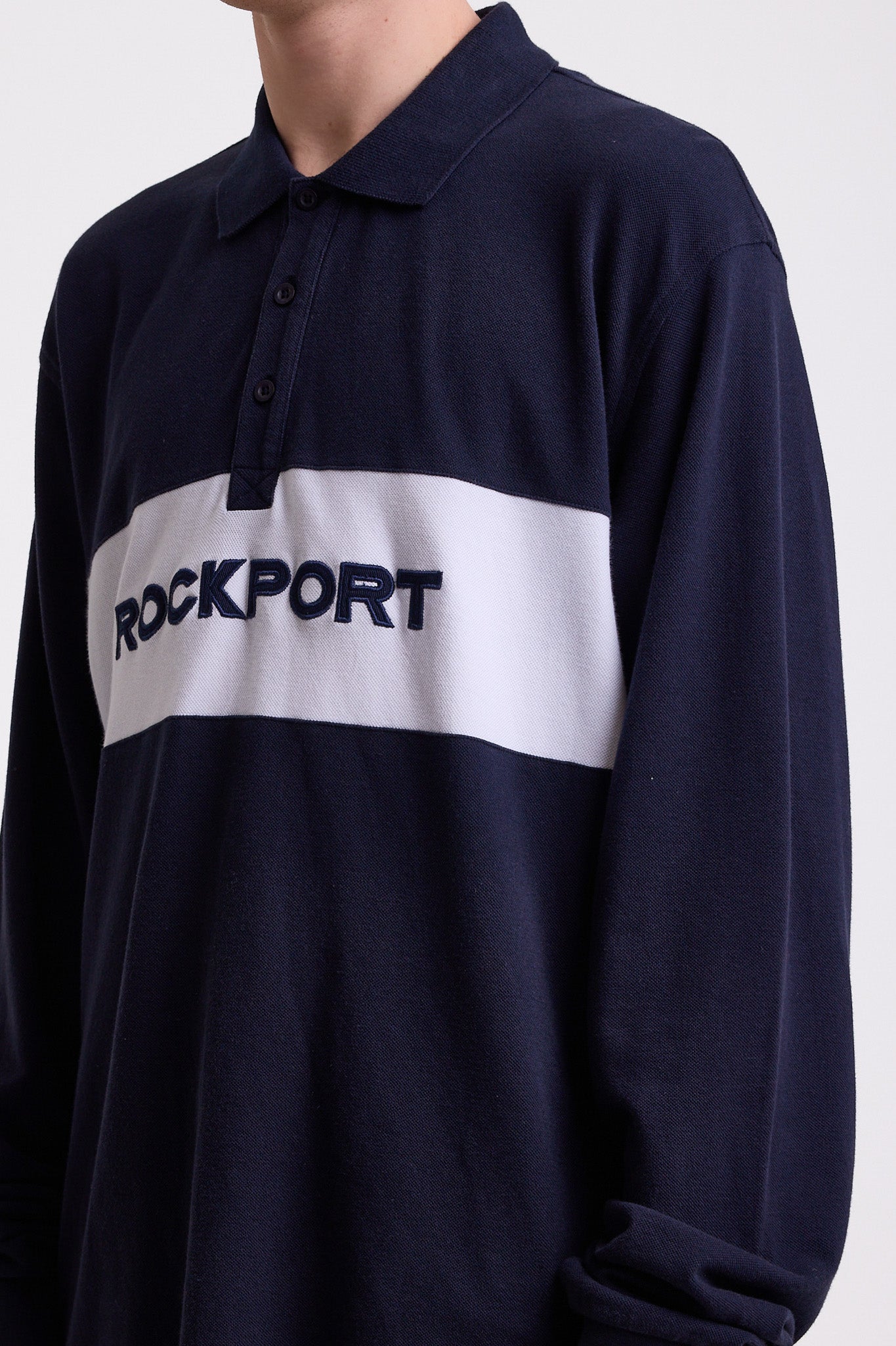 Navy long sleeve pique polo shirt with contrast chest panel and appliqué Rockport logo, worn by model