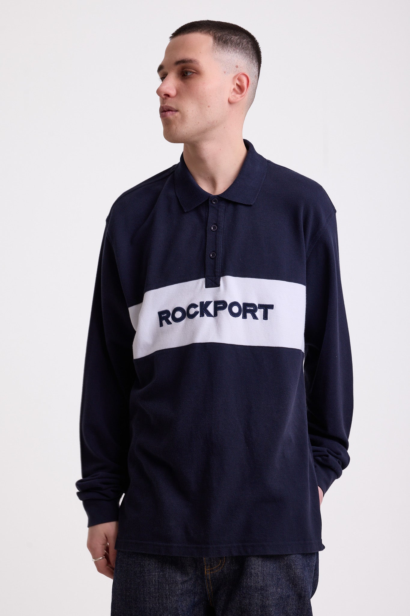 Navy long sleeve pique polo shirt with contrast chest panel and appliqué Rockport logo, worn by model