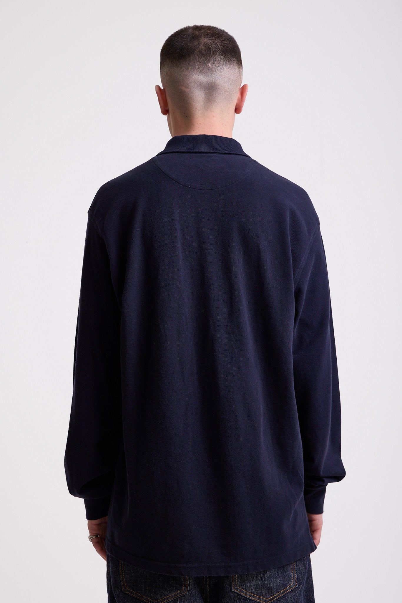 Navy long sleeve pique polo shirt with contrast chest panel and appliqué Rockport logo, worn by model