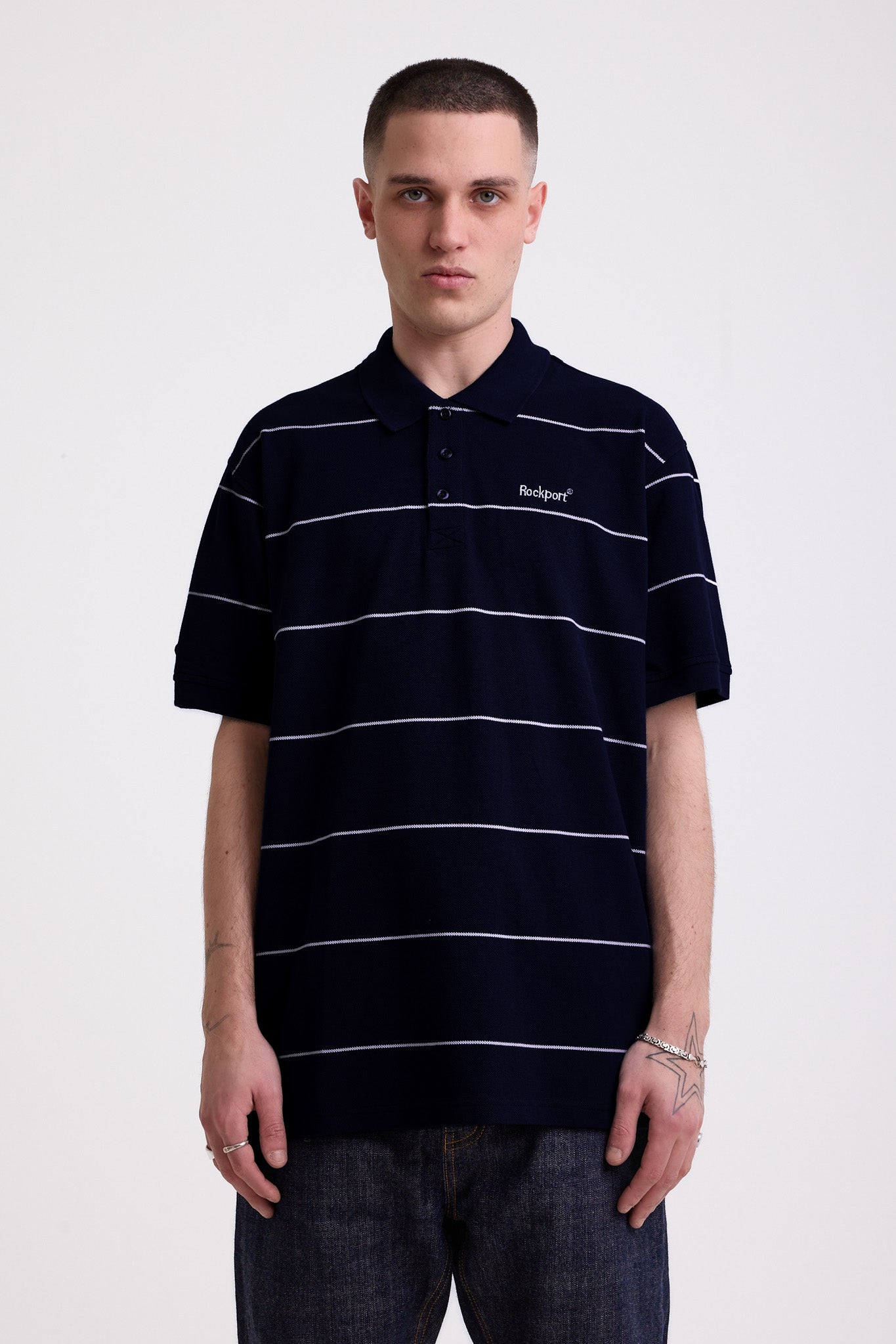 Navy and white striped pique polo shirt with embroidered Rockport logo, worn by model
