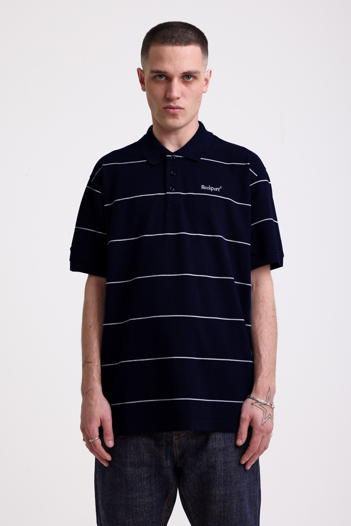 Navy and white striped pique polo shirt with embroidered Rockport logo, worn by model
