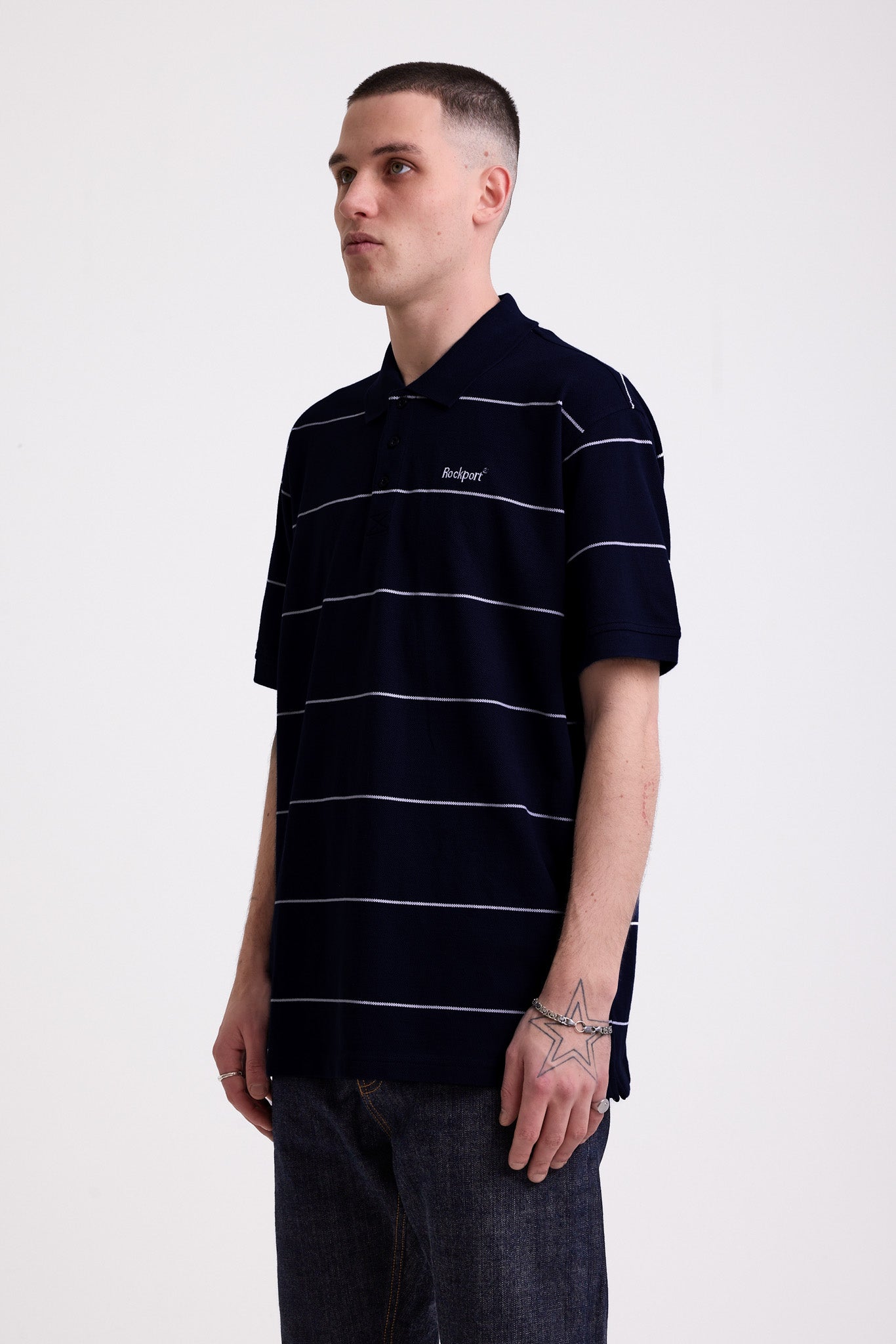 Navy and white striped pique polo shirt with embroidered Rockport logo, worn by model