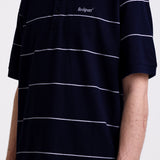 Navy and white striped pique polo shirt with embroidered Rockport logo, worn by model