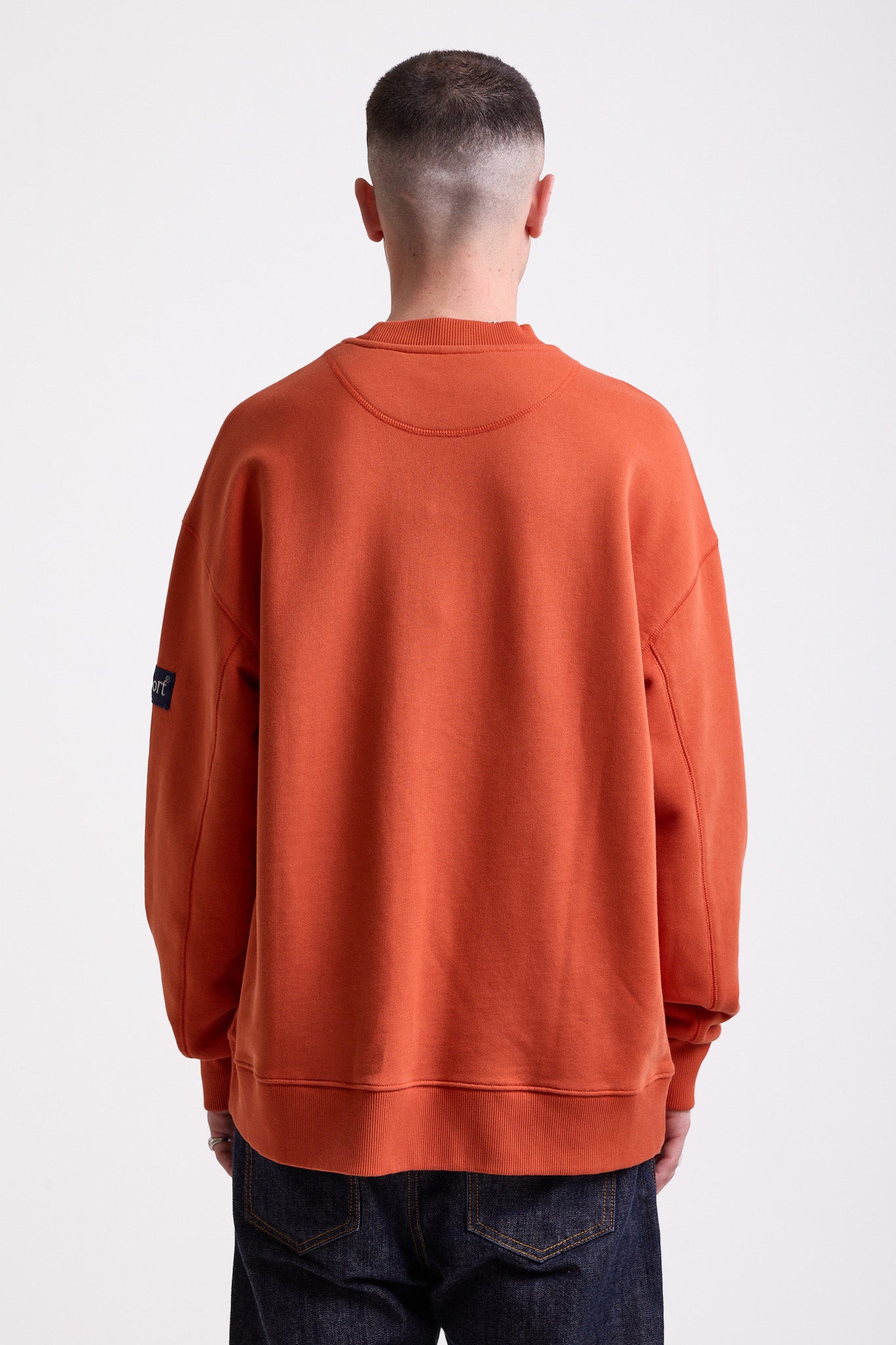 Burnt orange cotton crew neck sweatshirt with embroidered Rockport logo and american flag at chest, worn by model