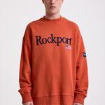 Burnt orange cotton crew neck sweatshirt with embroidered Rockport logo and american flag at chest, worn by model