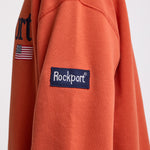Burnt orange cotton crew neck sweatshirt with embroidered Rockport logo and american flag at chest, worn by model