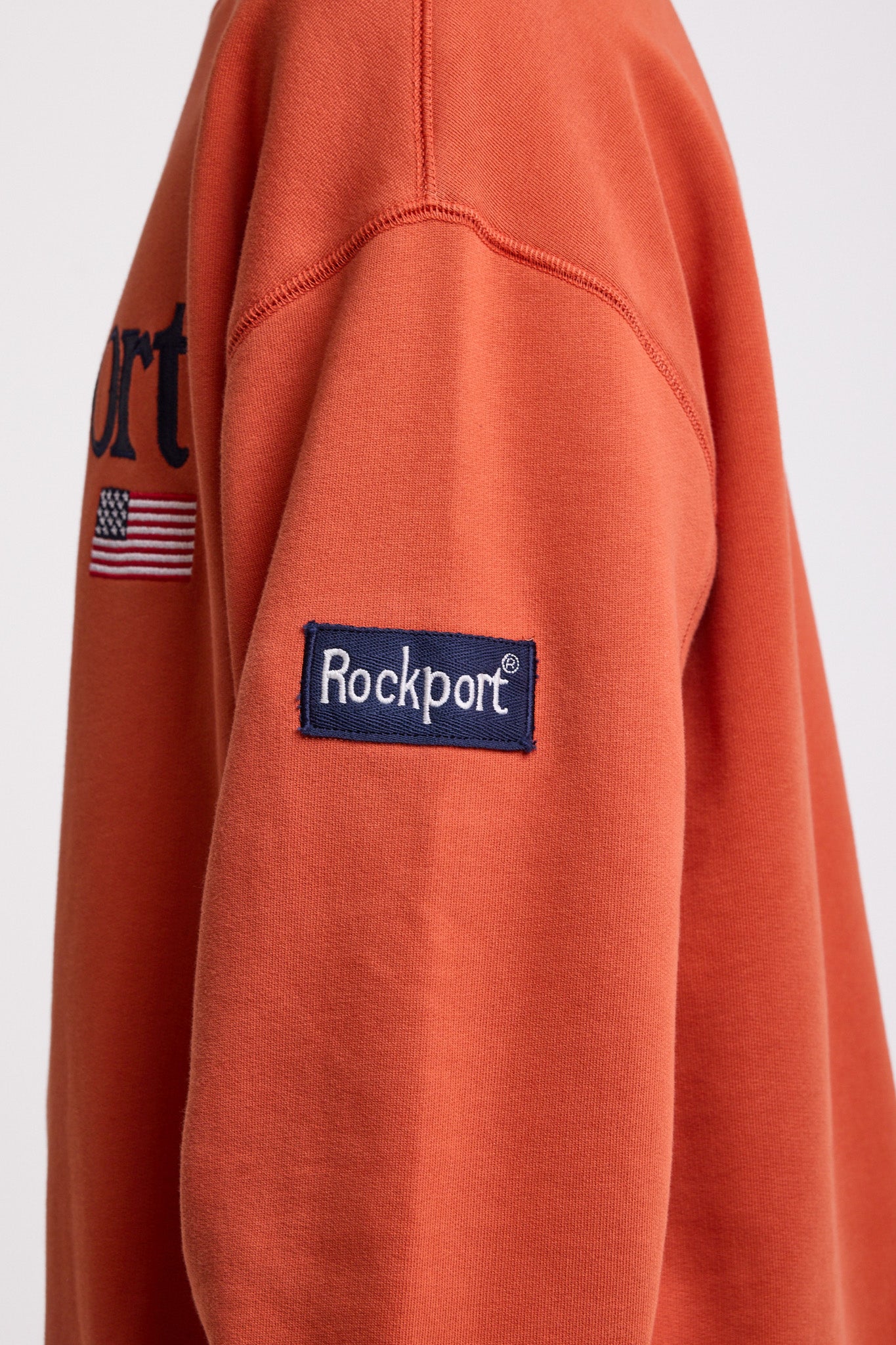 Burnt orange cotton crew neck sweatshirt with embroidered Rockport logo and american flag at chest, worn by model