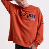 Burnt orange cotton crew neck sweatshirt with embroidered Rockport logo and american flag at chest, worn by model