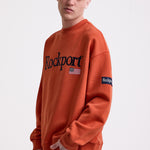 Burnt orange cotton crew neck sweatshirt with embroidered Rockport logo and american flag at chest, worn by model