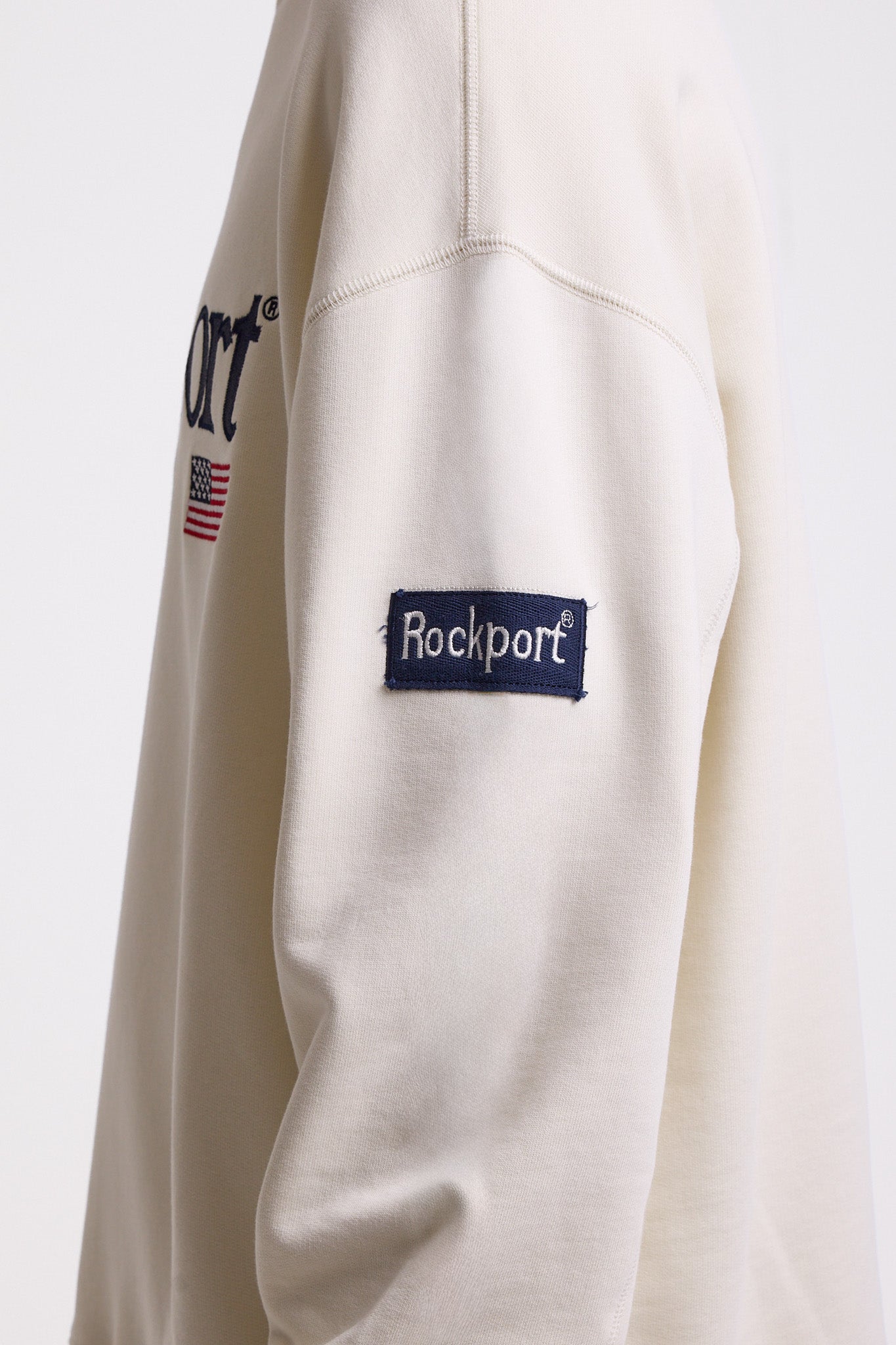 Ecru cotton crew neck sweatshirt with embroidered Rockport logo and american flag at chest, worn by model