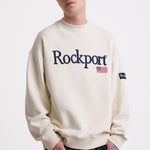 Ecru cotton crew neck sweatshirt with embroidered Rockport logo and american flag at chest, worn by model
