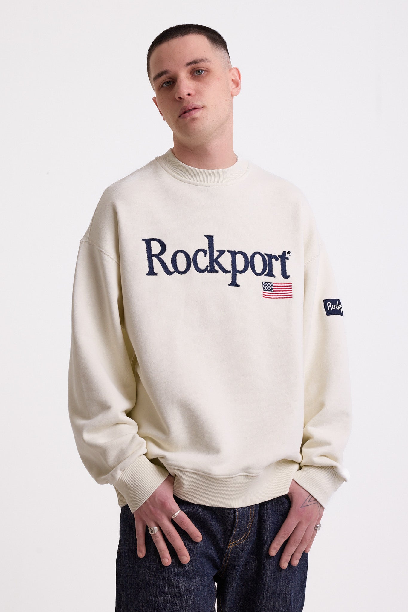 Ecru cotton crew neck sweatshirt with embroidered Rockport logo and american flag at chest, worn by model