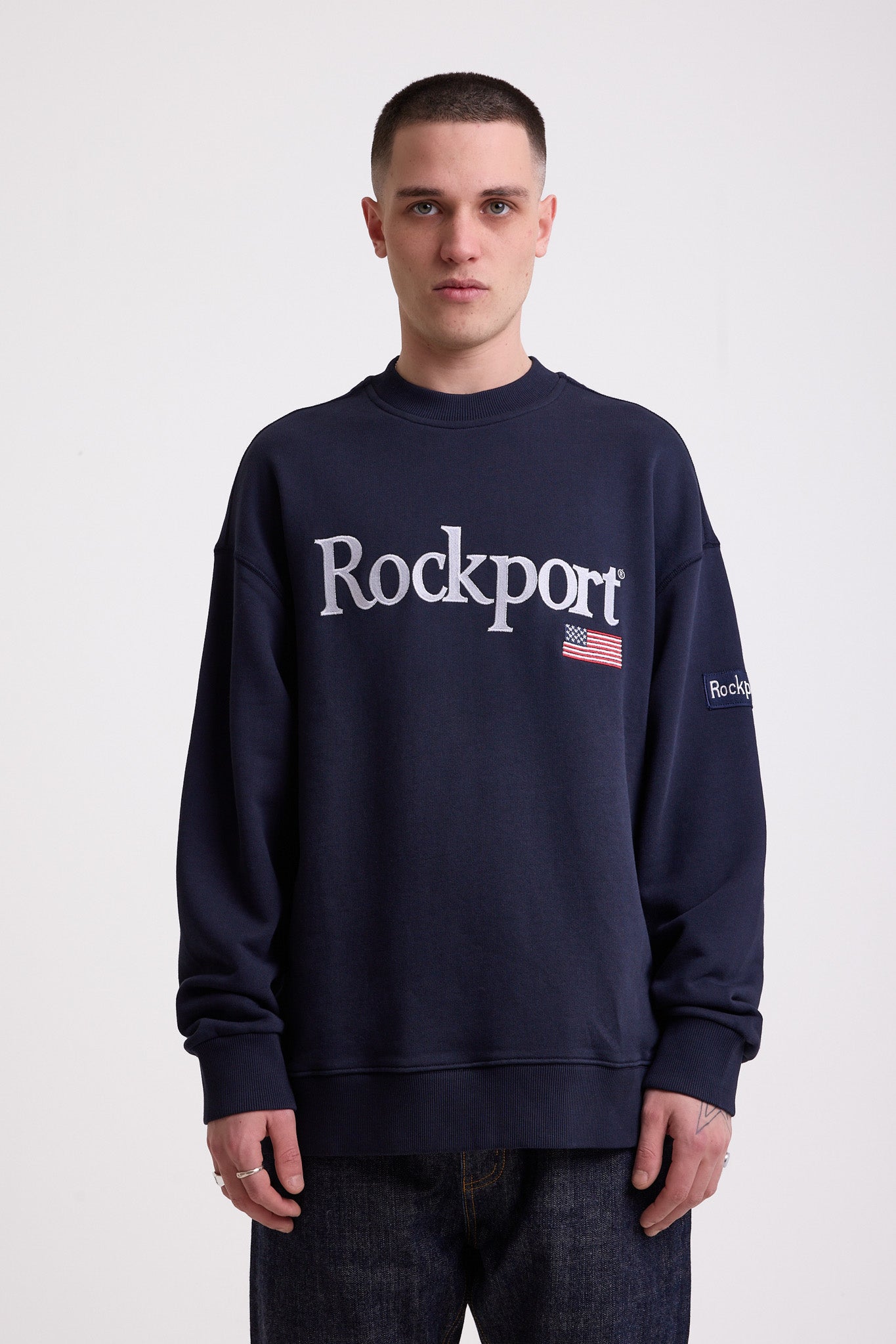 Navy cotton crew neck sweatshirt with embroidered Rockport logo and american flag at chest, worn by model