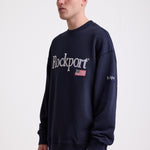 Navy cotton crew neck sweatshirt with embroidered Rockport logo and american flag at chest, worn by model