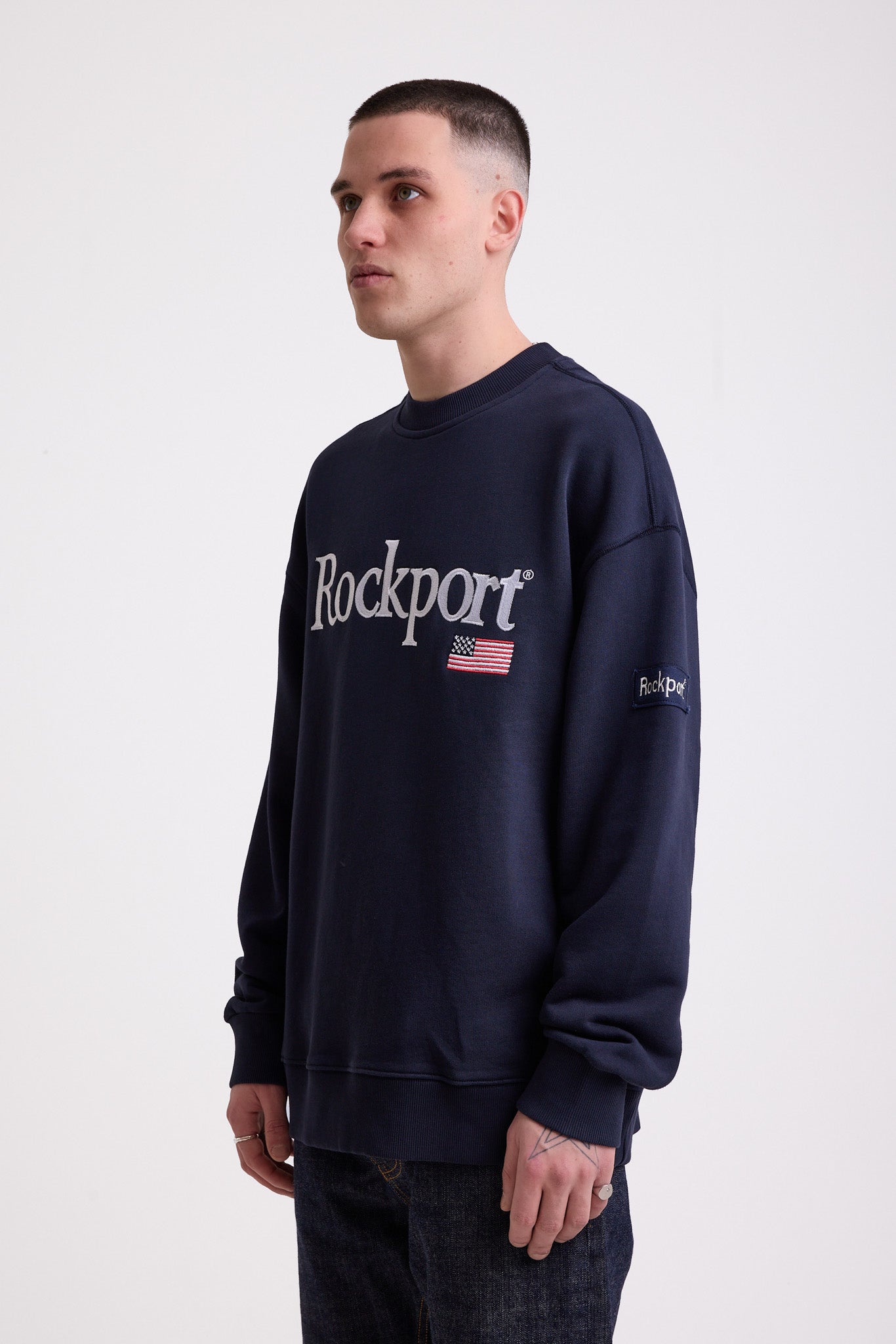 Navy cotton crew neck sweatshirt with embroidered Rockport logo and american flag at chest, worn by model