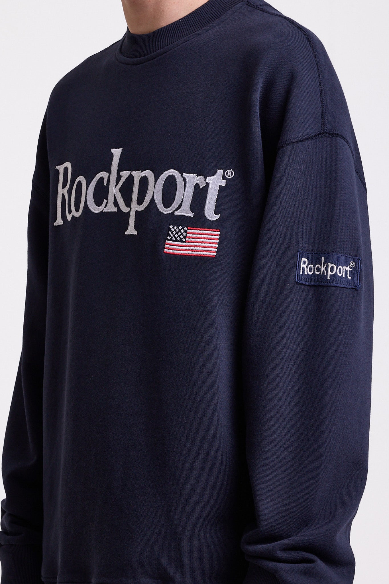 Navy cotton crew neck sweatshirt with embroidered Rockport logo and american flag at chest, worn by model